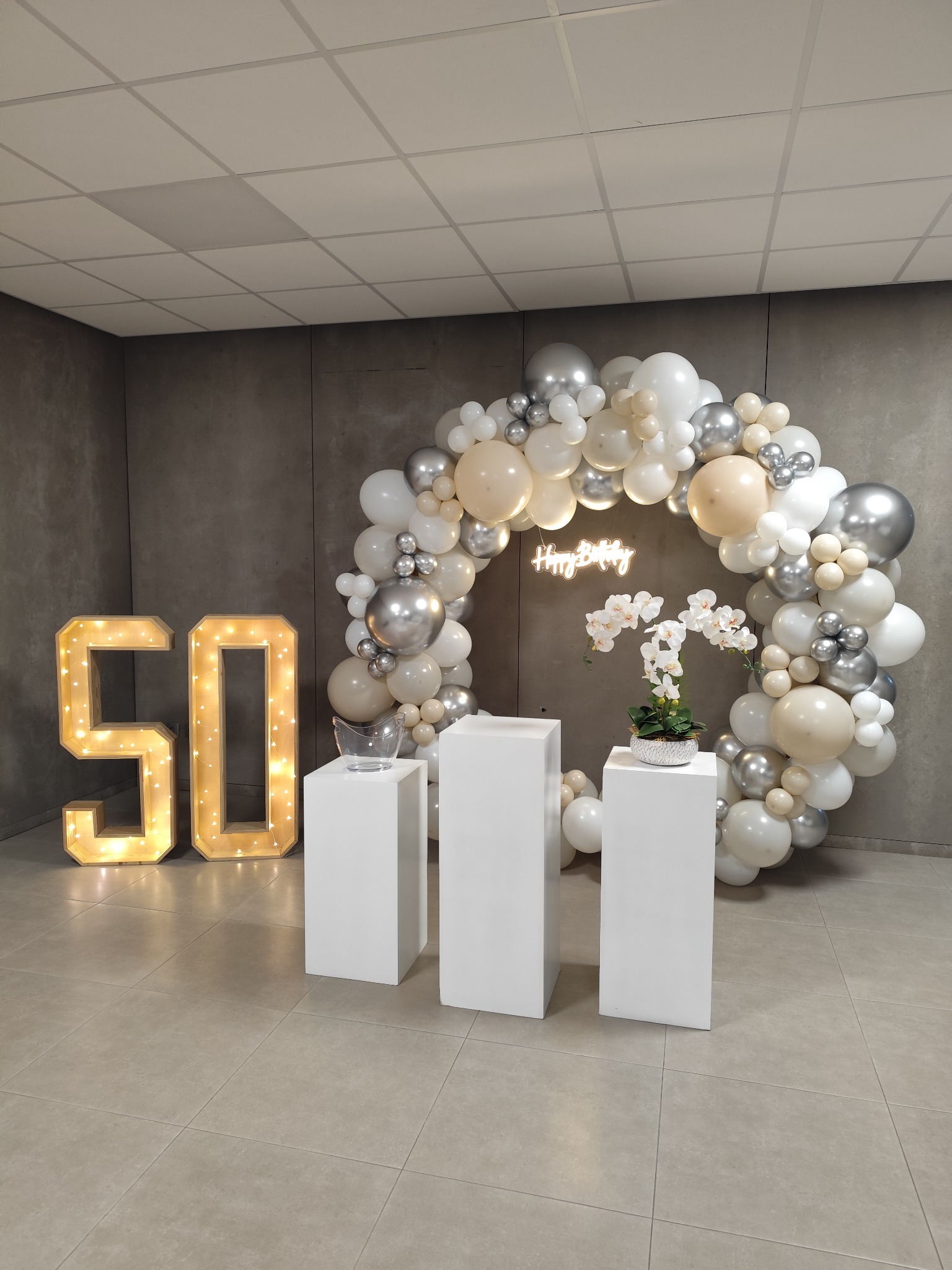 Decoração dos 50 anos com números luminosos e balões brancos, prateados e champanhe