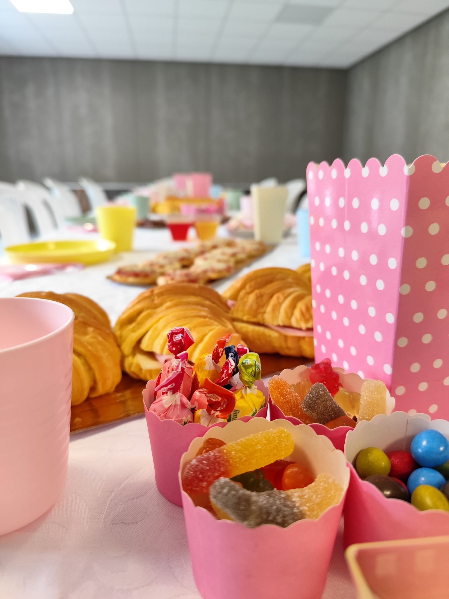 Mesa de festa com doces, croissants e caixas cor-de-rosa às bolinhas